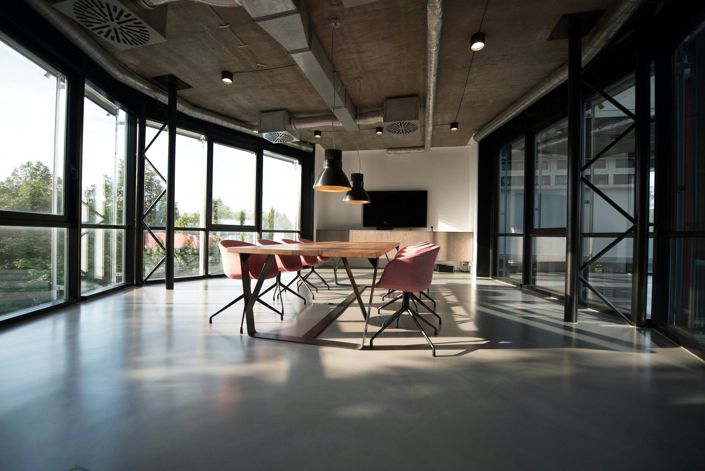 A sunlit meeting room with a long table and glass walls