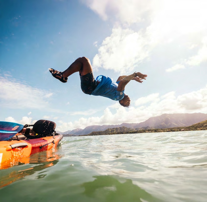 A person wearing Teva sandals leaps from a kayak into the water