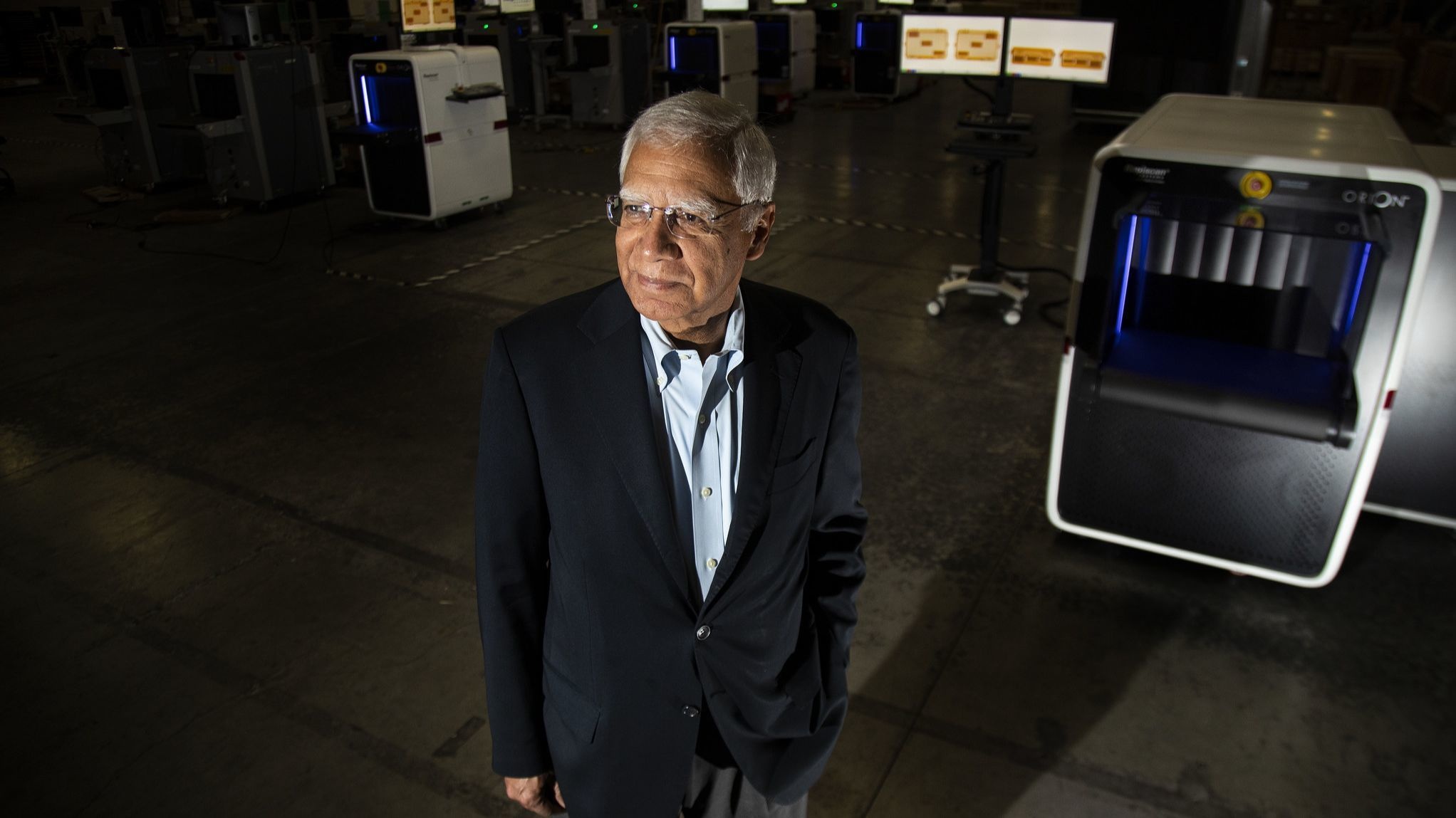 Deepak Chopra standing on a factory floor among Rapiscan security scanning machines
