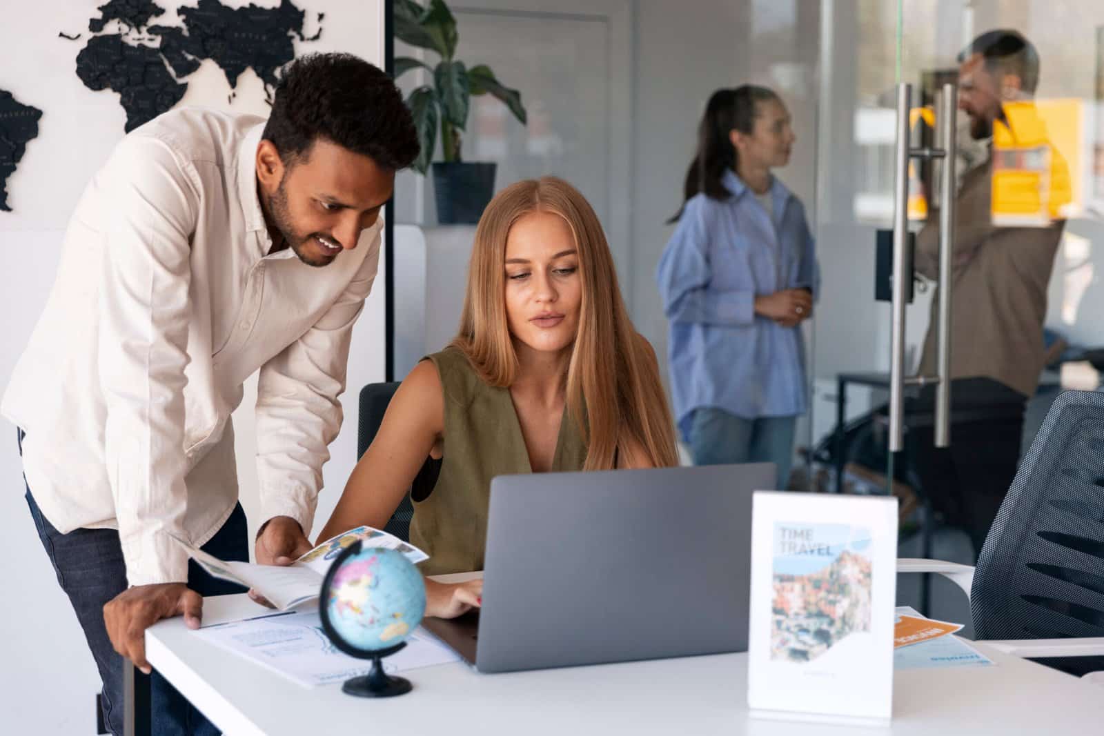 Colleagues gathered around a table with laptops in a bright office