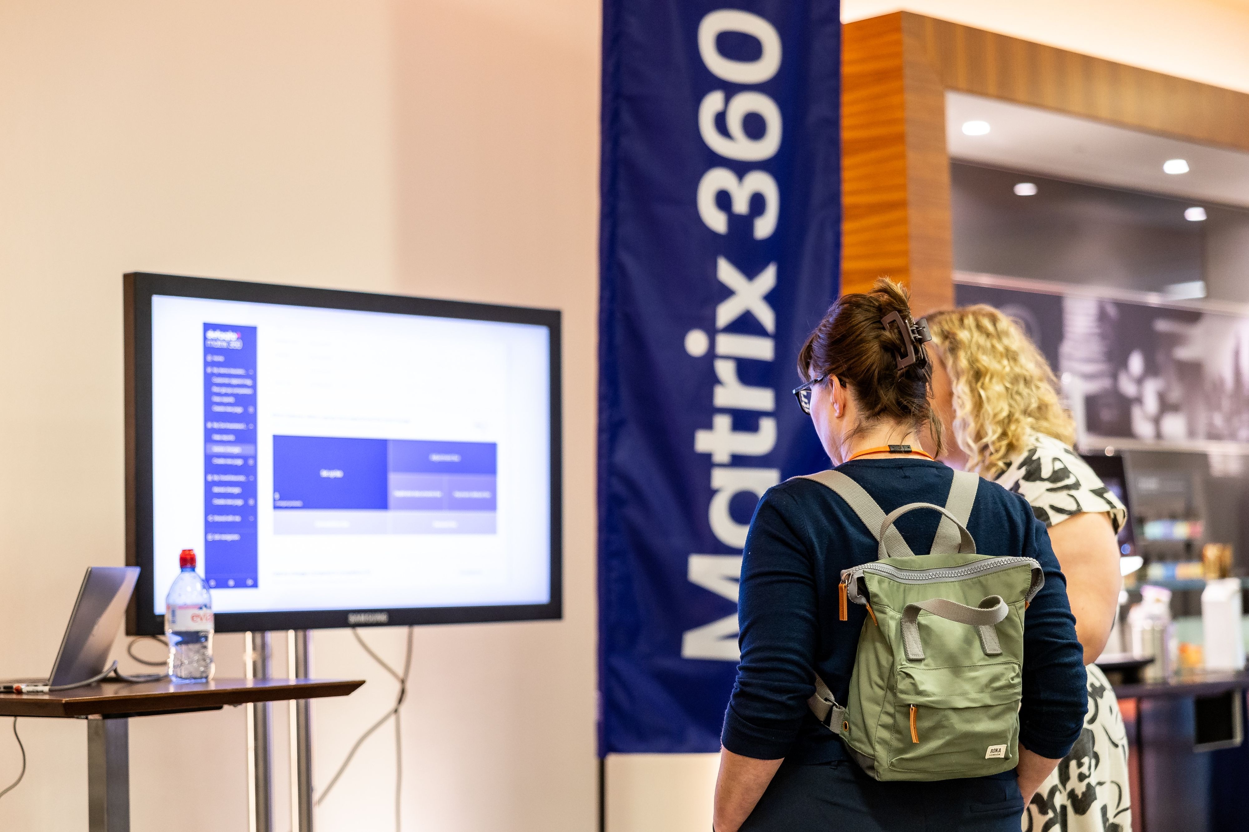 Visitors looking at a Matrix 360 demonstration screen at a Defaqto event