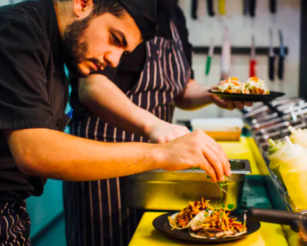Restaurant kitchen staff finishing plates of food at the pass