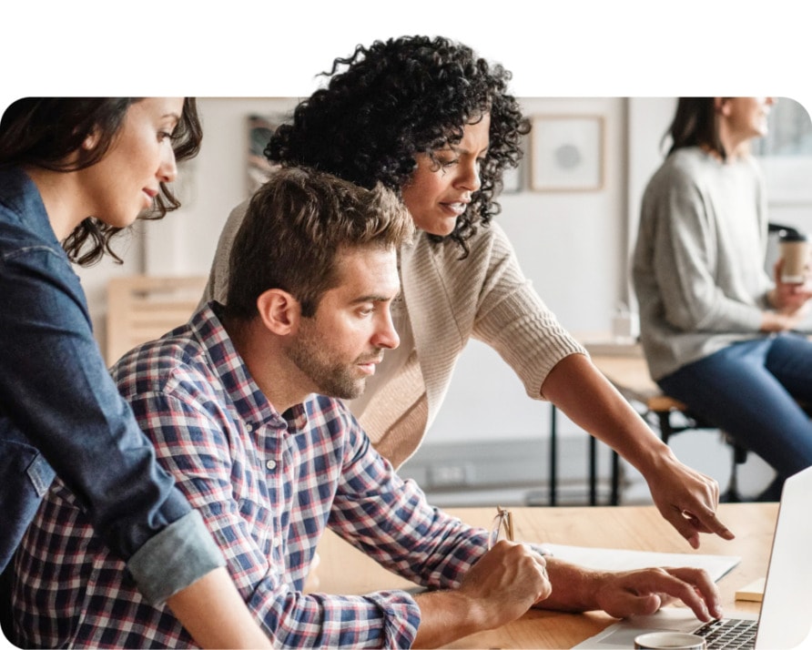 Three colleagues working together around a laptop