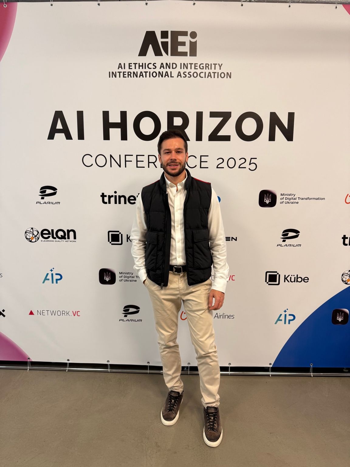 Den Burenok standing in front of the AI Horizon Conference 2025 backdrop