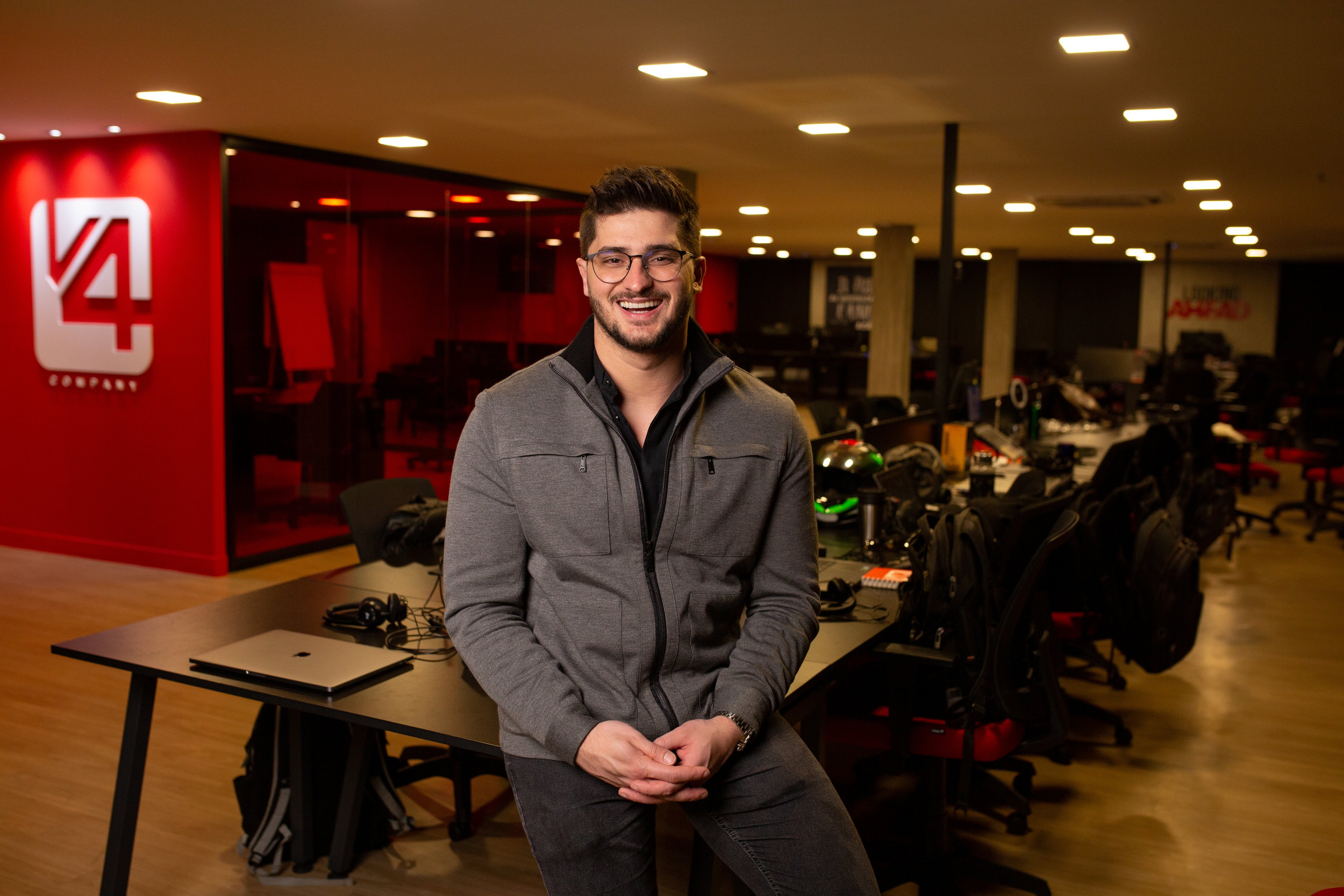 Dener Lippert sitting at a desk in V4’s open-plan office, with workstations behind him