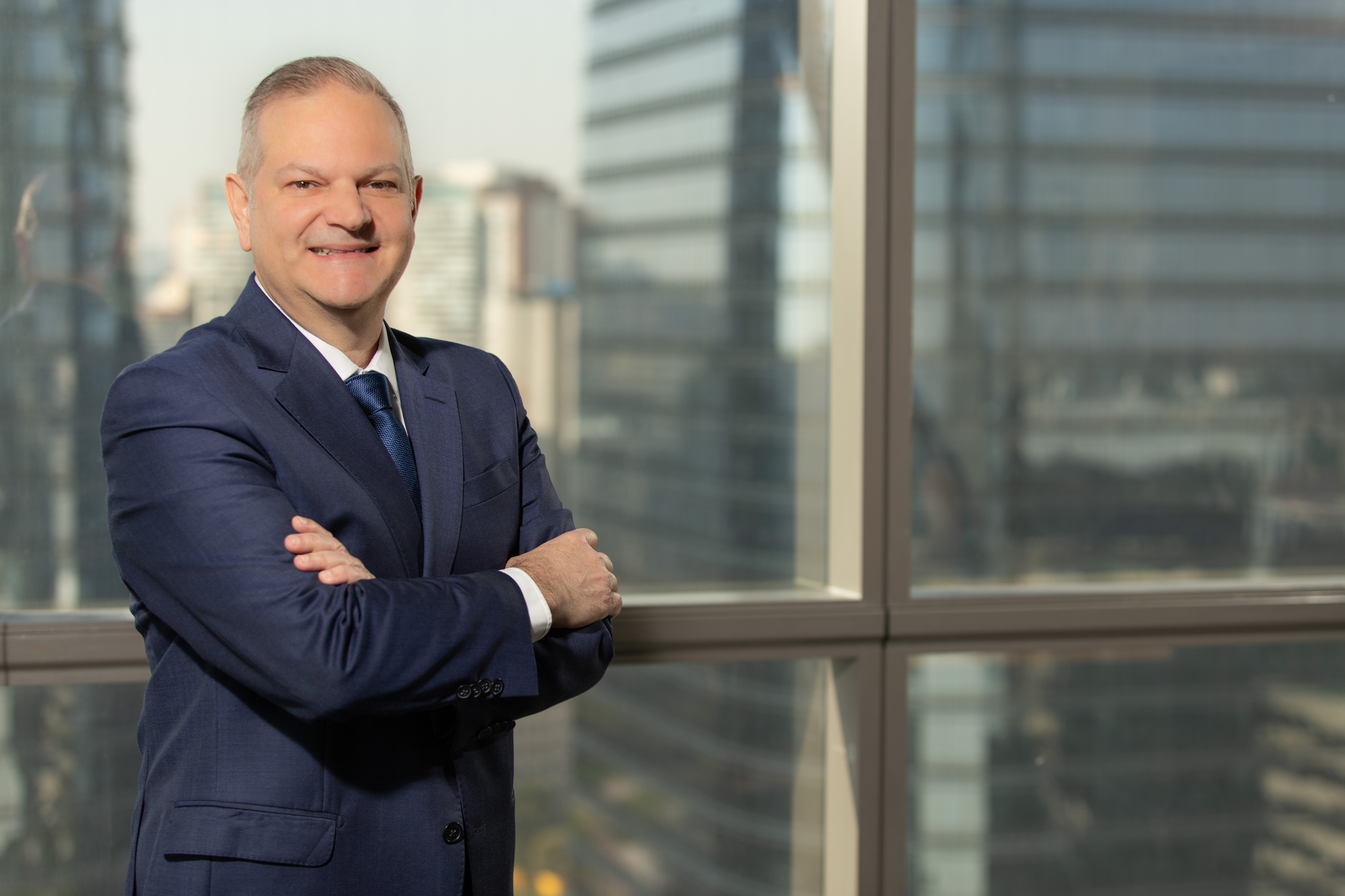 Denis Ferreira in a blue suit, standing beside office windows