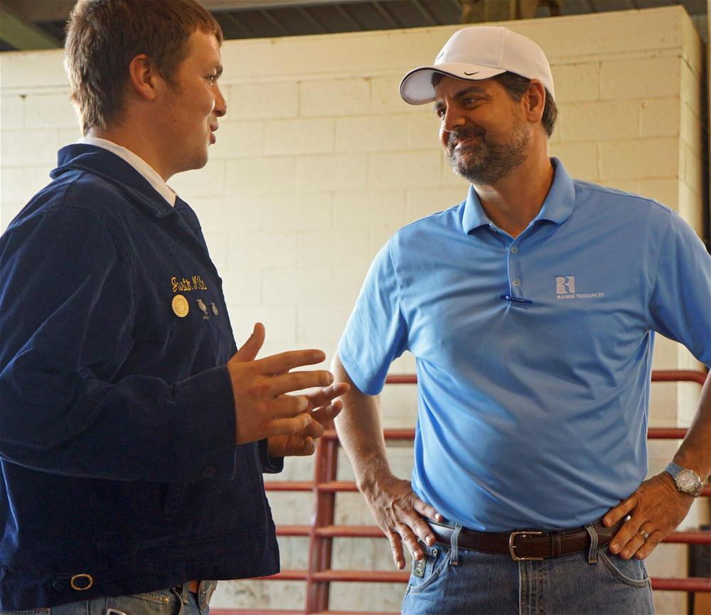 Dennis Degner, at right in a blue Range polo, speaking with an FFA member at the Washington County Fair