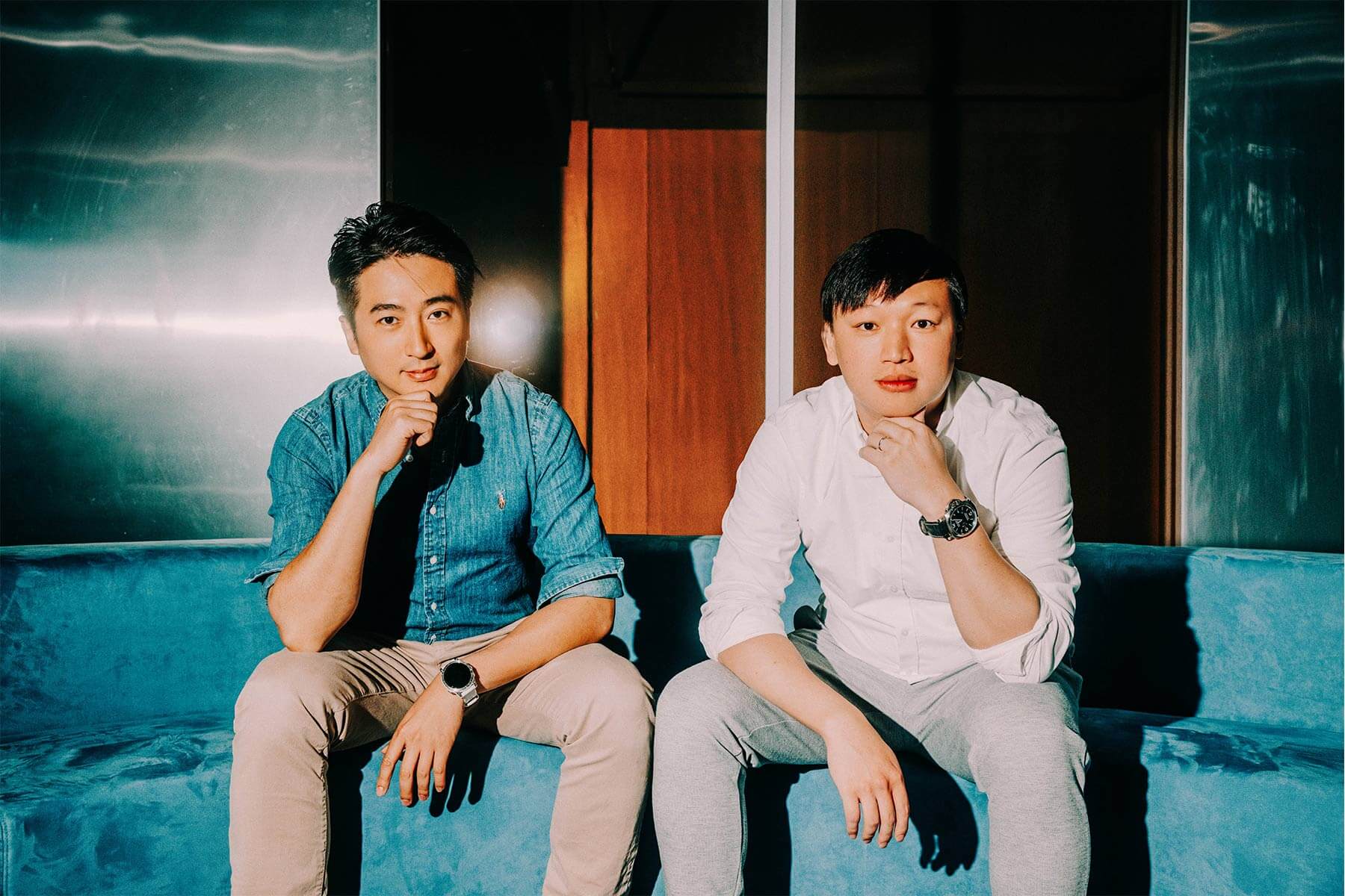 PressPlay co-founders Dennis Lin, left, and Rob Kuo seated together on a blue sofa