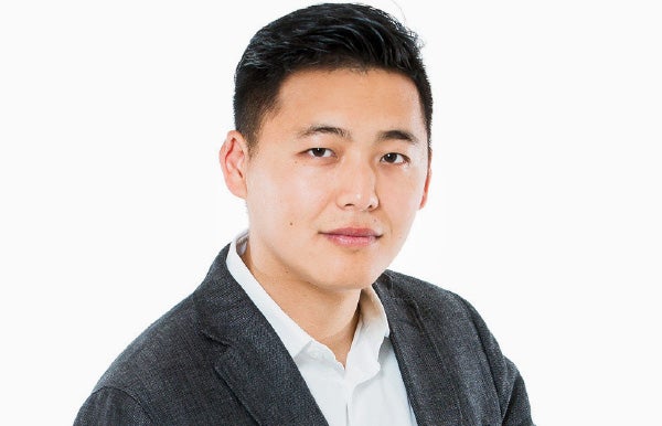 Dennis Liu in a dark jacket and white shirt, photographed for a 2015 business feature