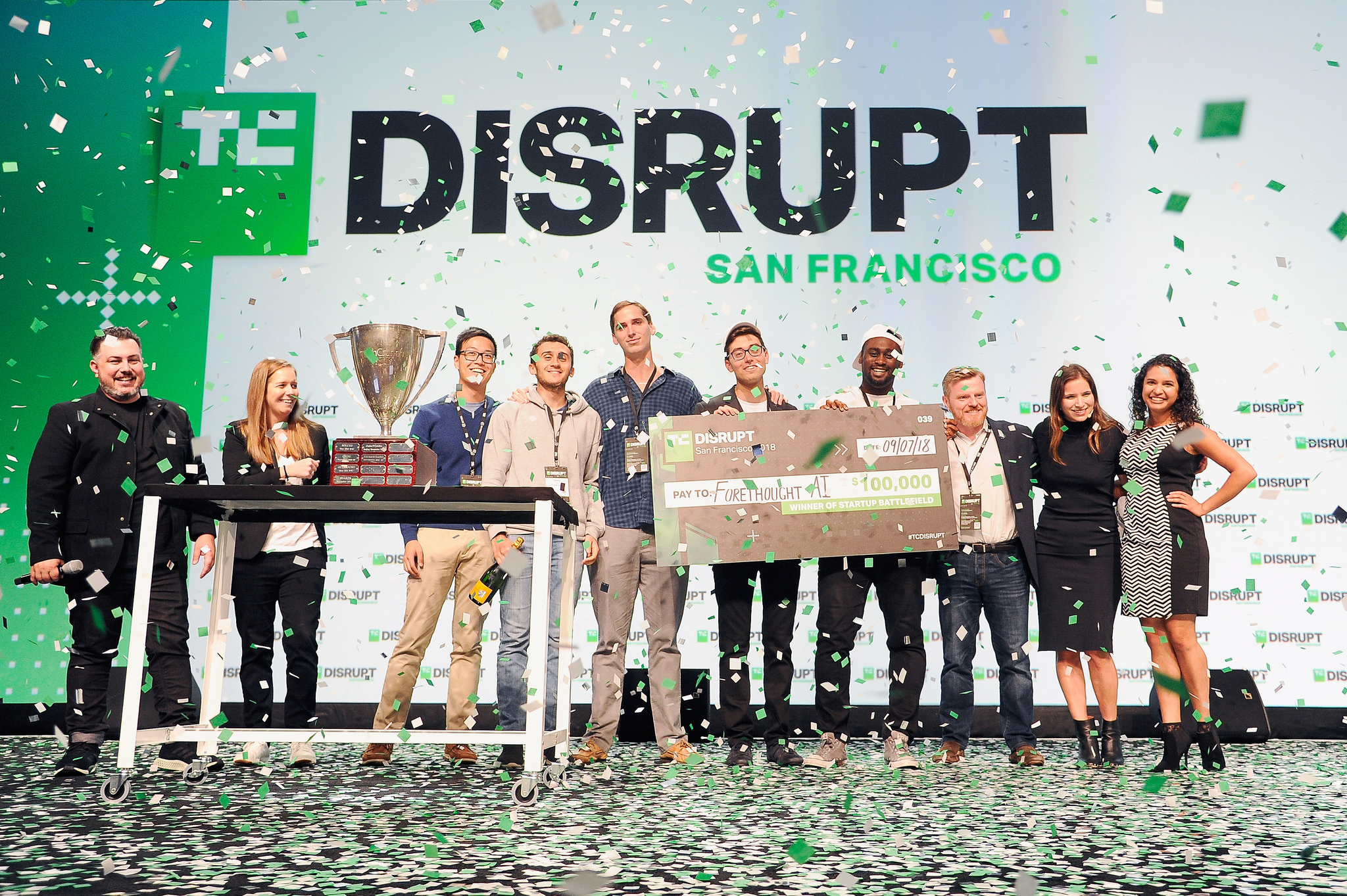 Deon Nicholas and the Forethought team celebrating the 2018 Startup Battlefield win with TechCrunch staff, a trophy and falling confetti