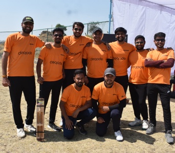 Deqode cricket squad posing in orange company shirts with cricket bats