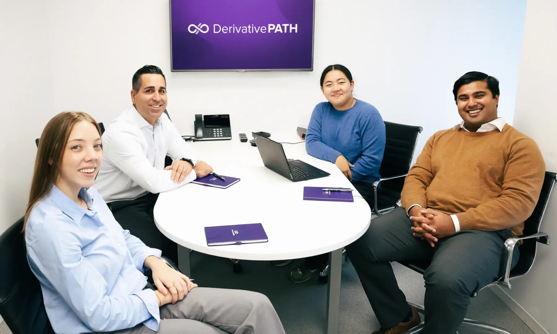 Four Derivative Path team members seated around a meeting table