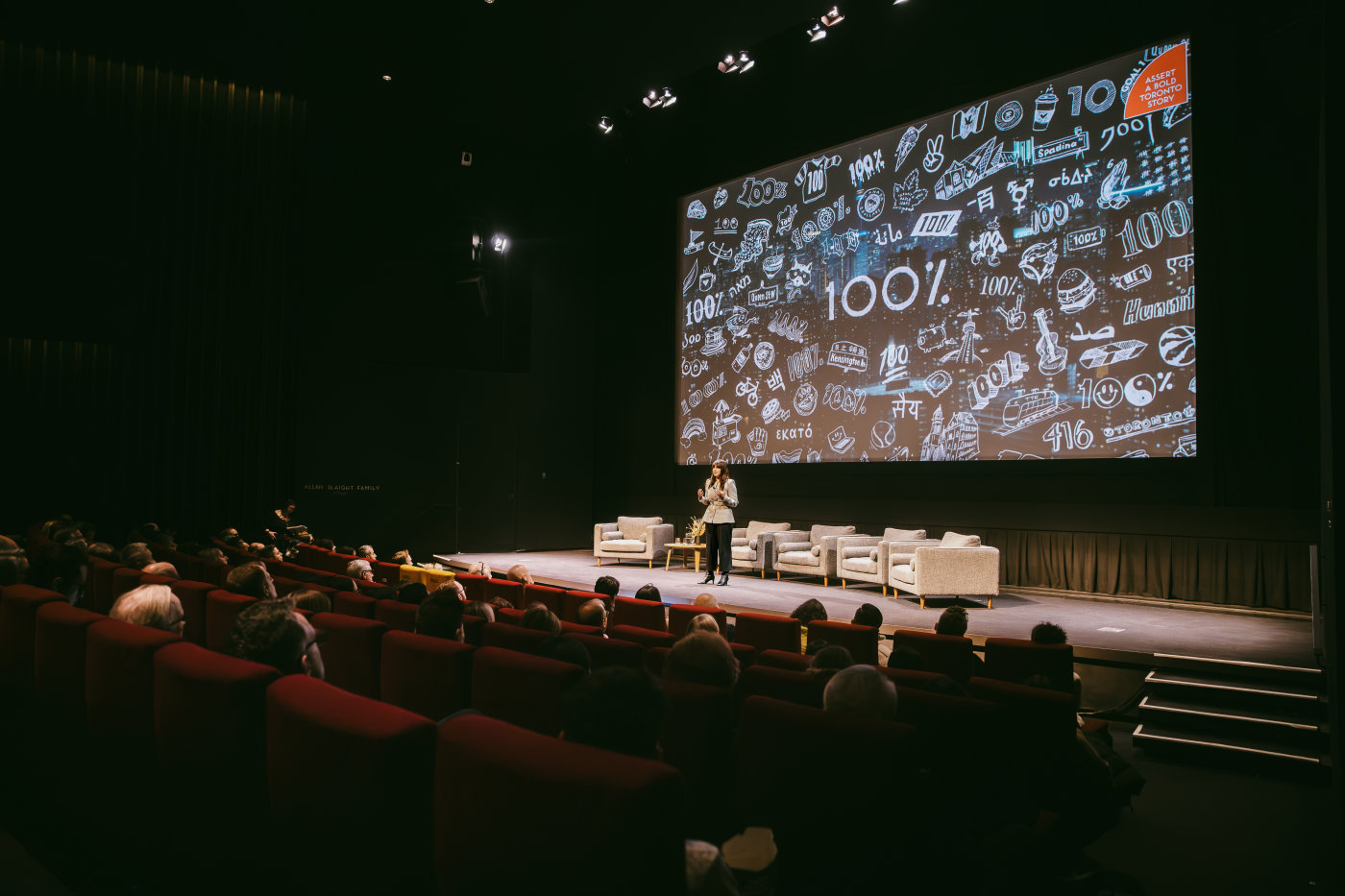 Paula Port presents the Toronto 100% campaign to an audience in a theatre