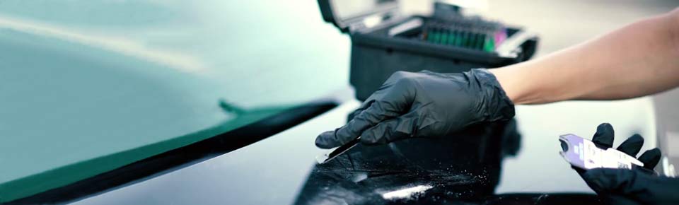Gloved operator collecting a surface sample with a MobileDetect swab beside a field kit