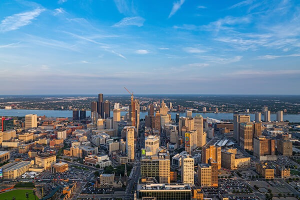 Aerial view of downtown Detroit and the Detroit River under a blue sky