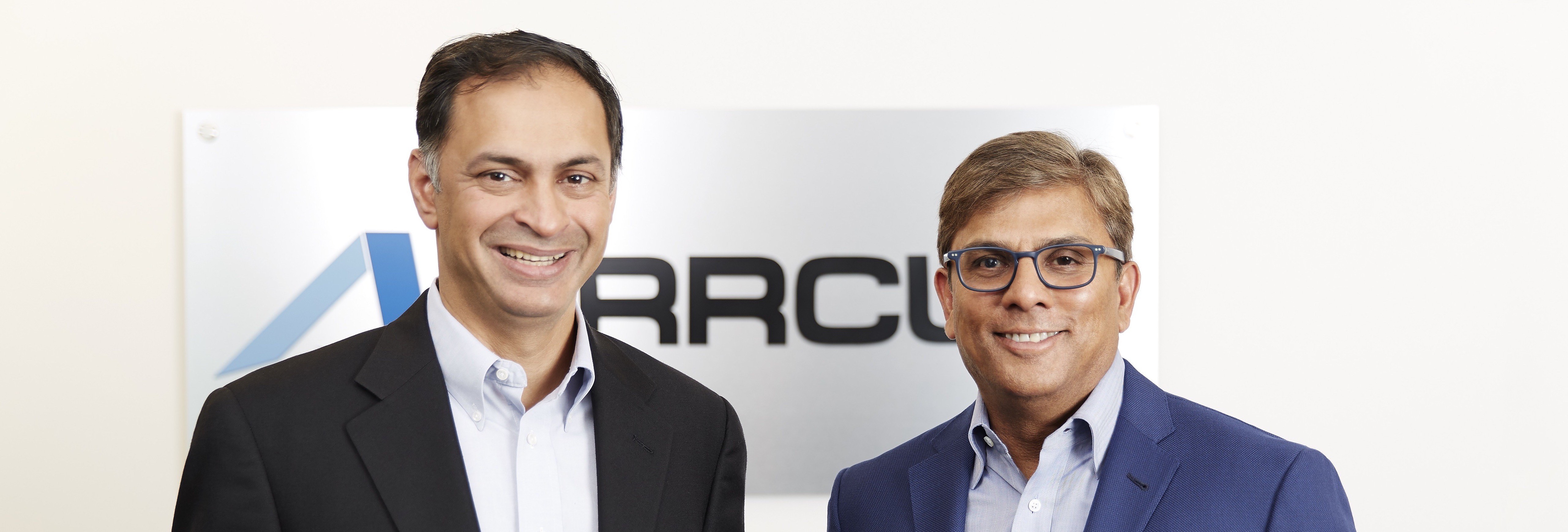 Arrcus co-founders Keyur Patel, left, and Devesh Garg, right, standing together in front of the company sign.