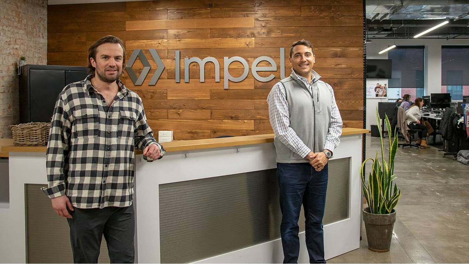 Michael Quigley, left, and Devin Daly, right, standing at the reception desk in Impel’s office