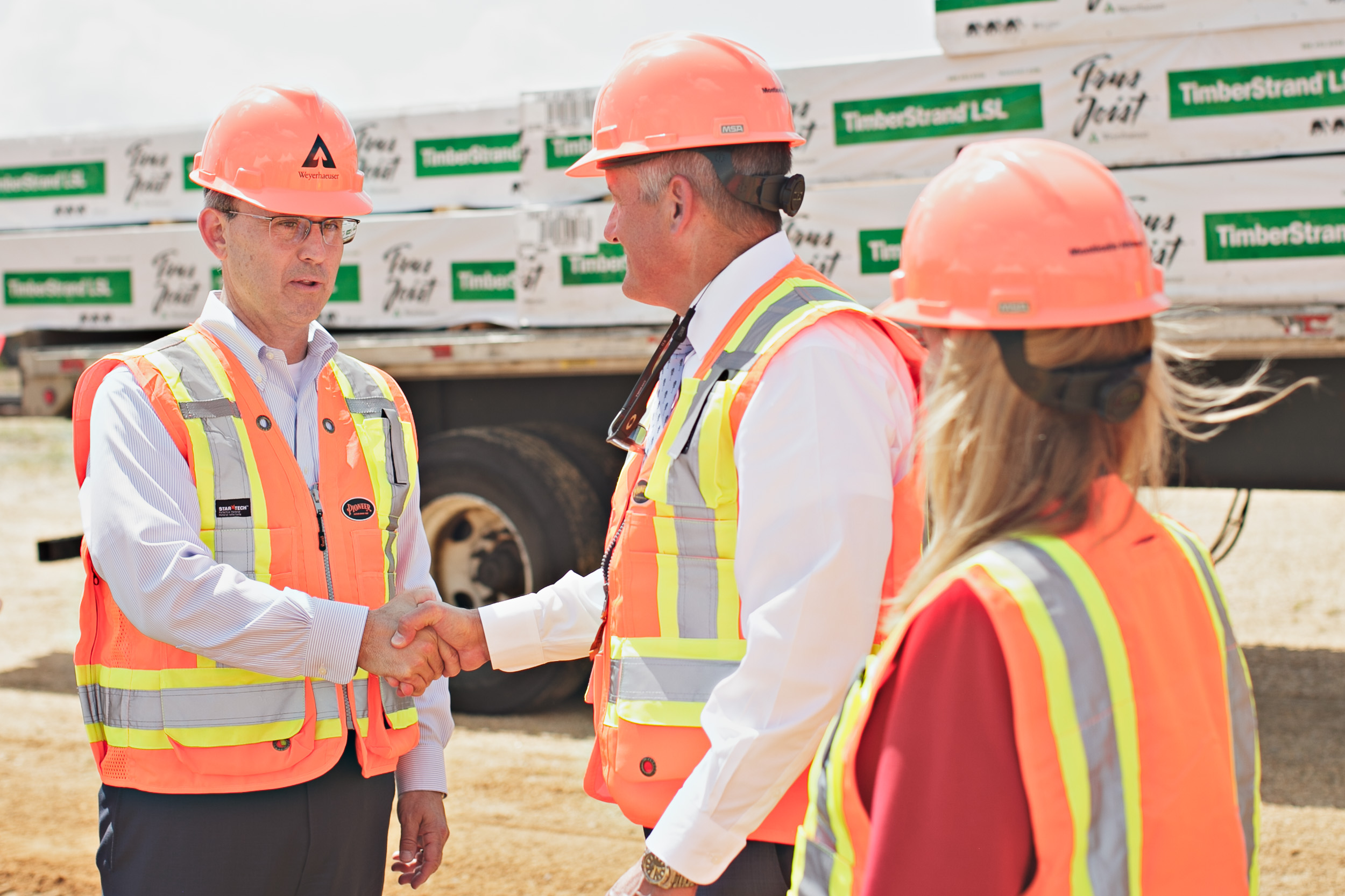 Devin Stockfish, at left in an orange hard hat, greeting attendees at the Arkansas TimberStrand groundbreaking.