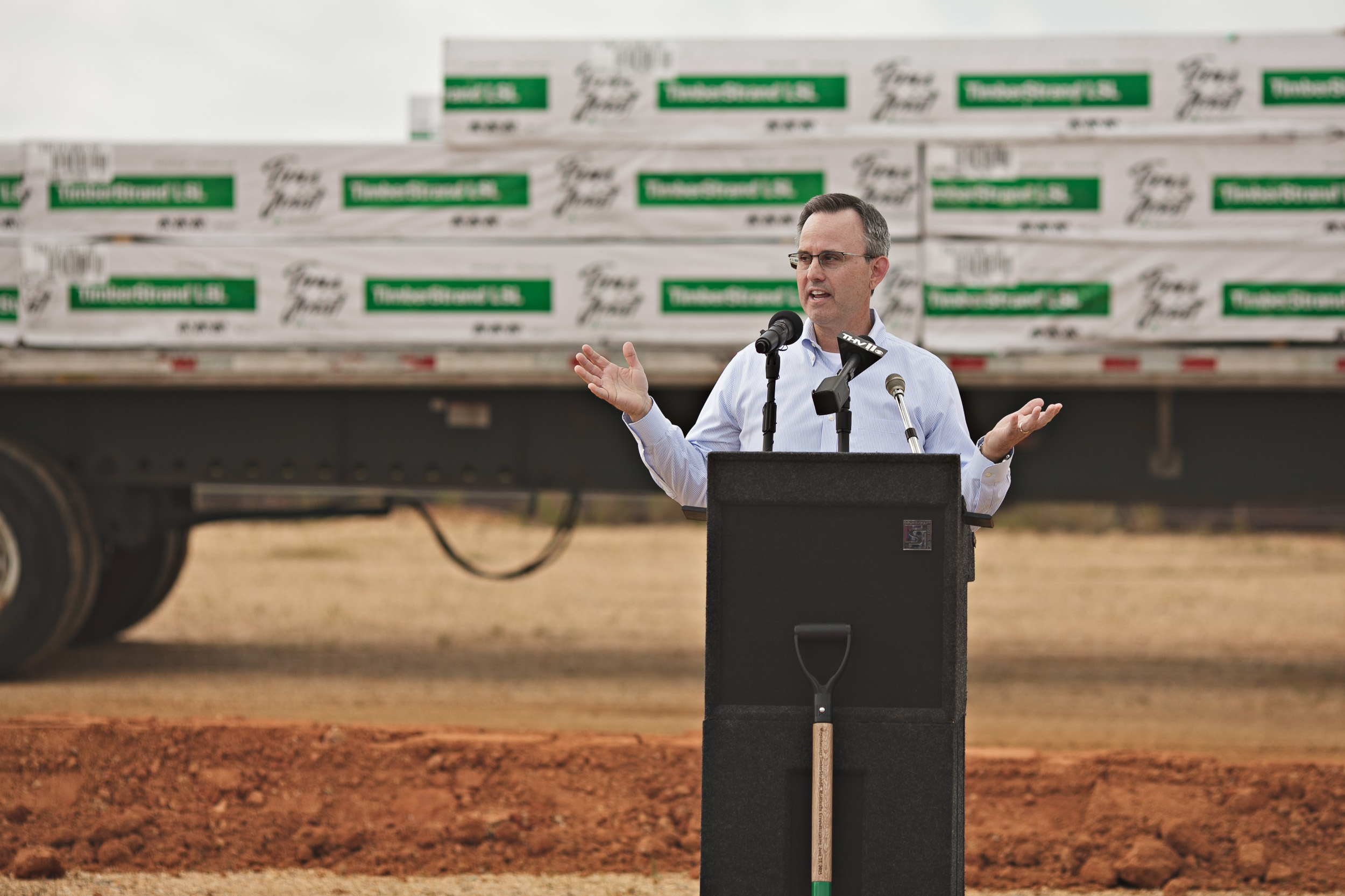 Devin Stockfish speaking at a podium in front of TimberStrand products at the Arkansas groundbreaking.