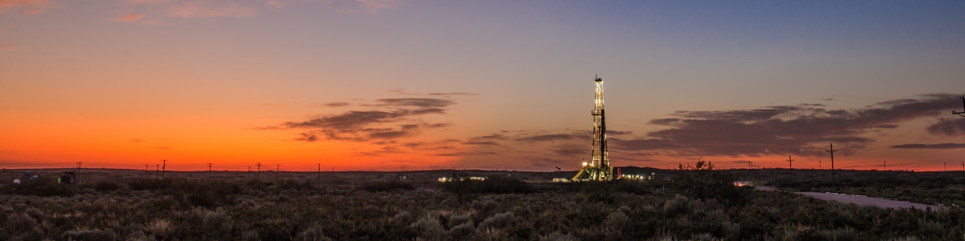 A lit drilling rig beneath a sunset in Devon’s Delaware Basin operations