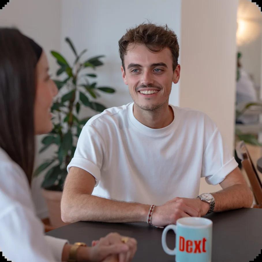 Two people talking across a table in photography from Dext’s company page