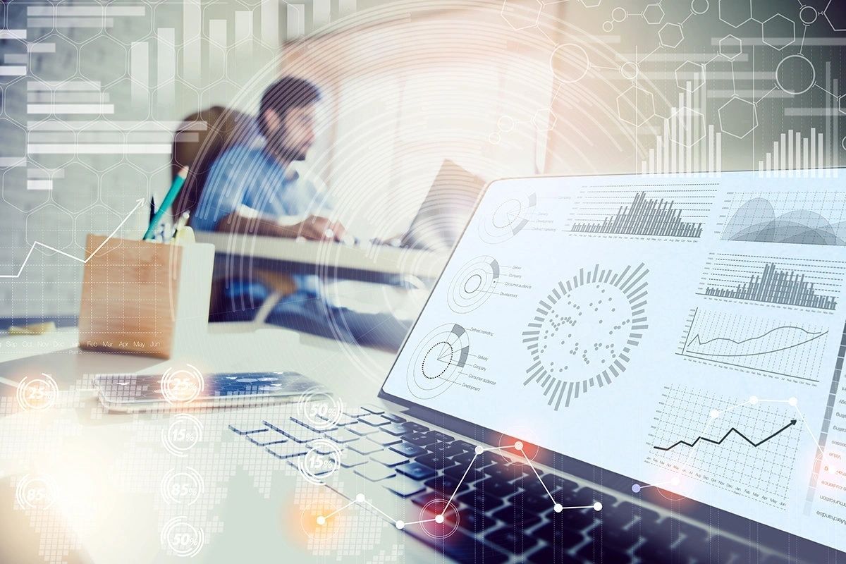 Laptop and printed charts in an analytics illustration used on DFG’s historical website