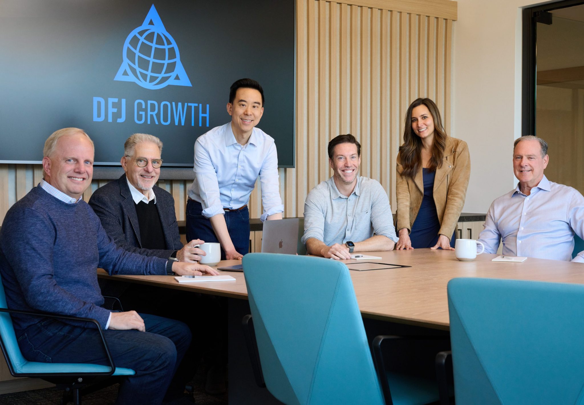 Six DFJ Growth team members gathered around a conference table