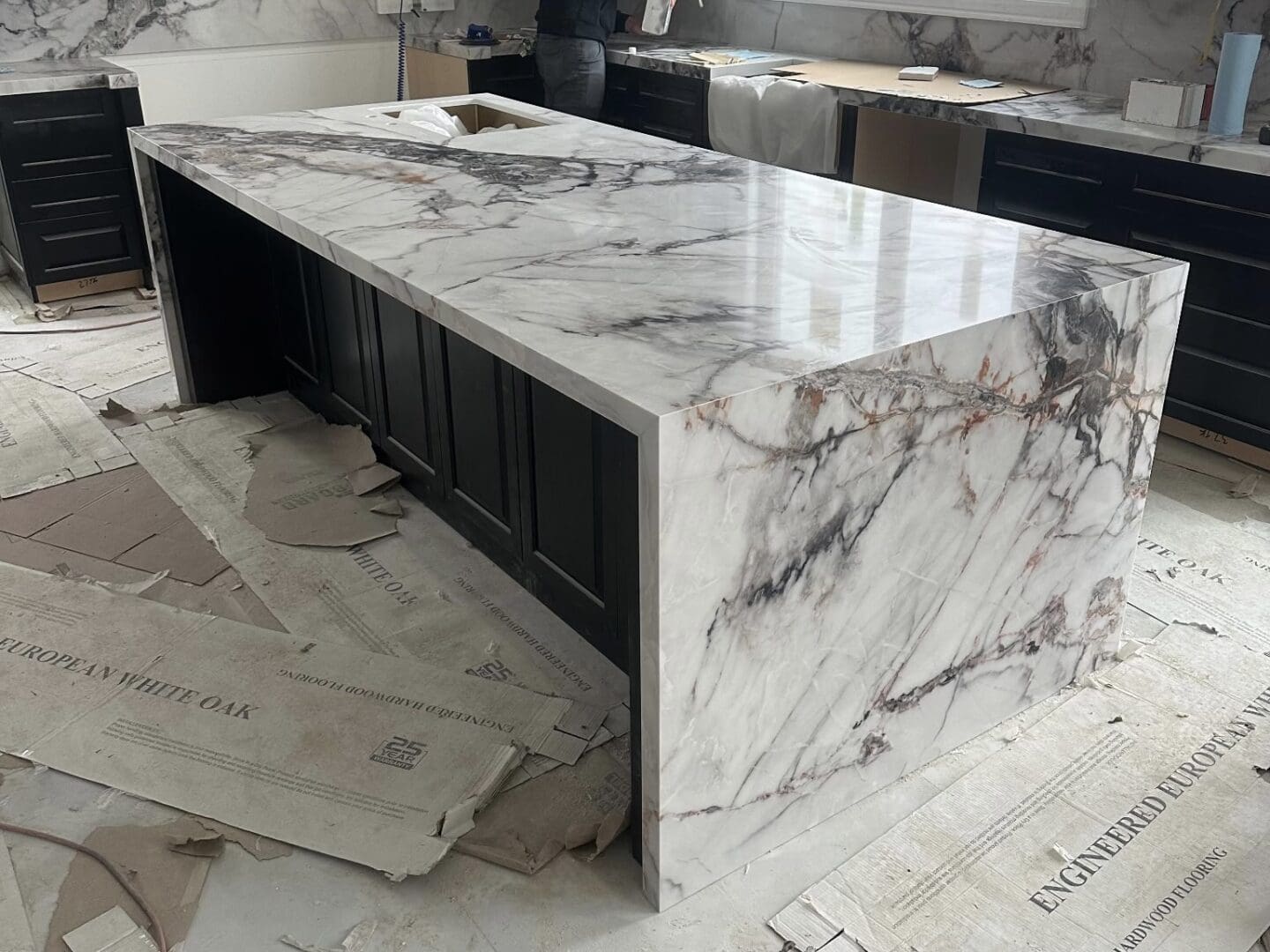 A veined stone kitchen island being installed during a renovation