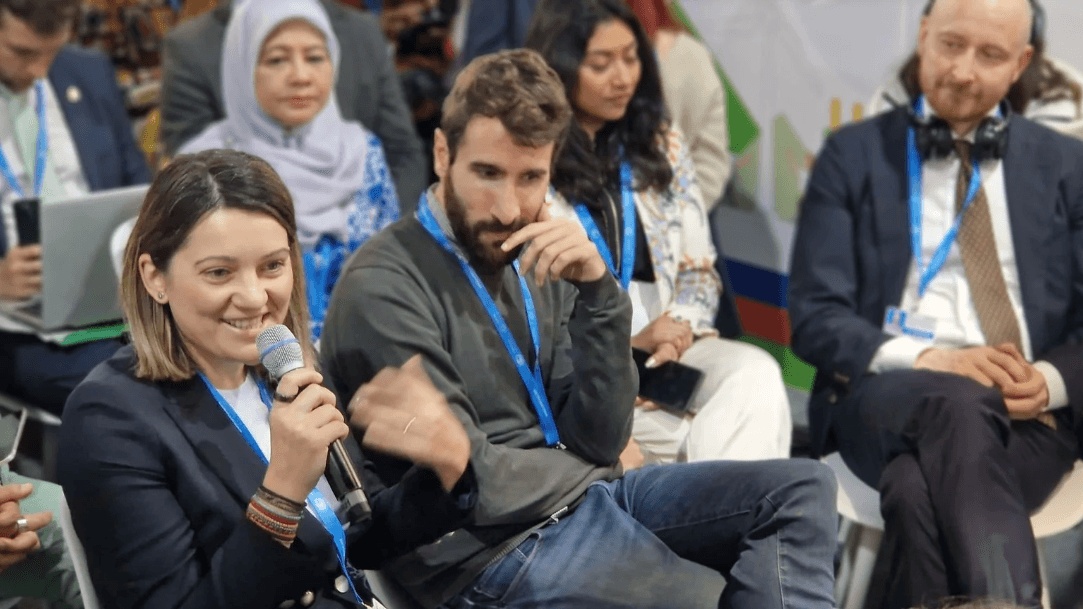 Diana Dumitrescu speaks into a microphone during a seated COP29 discussion in Baku
