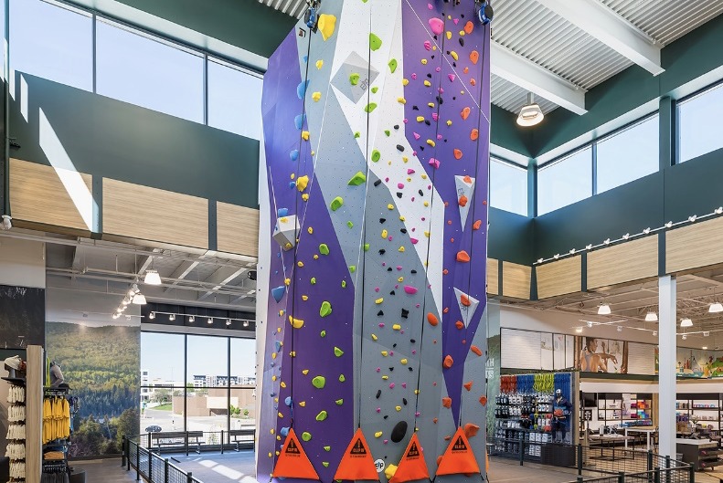 A climbing wall with colorful holds and safety ropes inside DICK’S House of Sport
