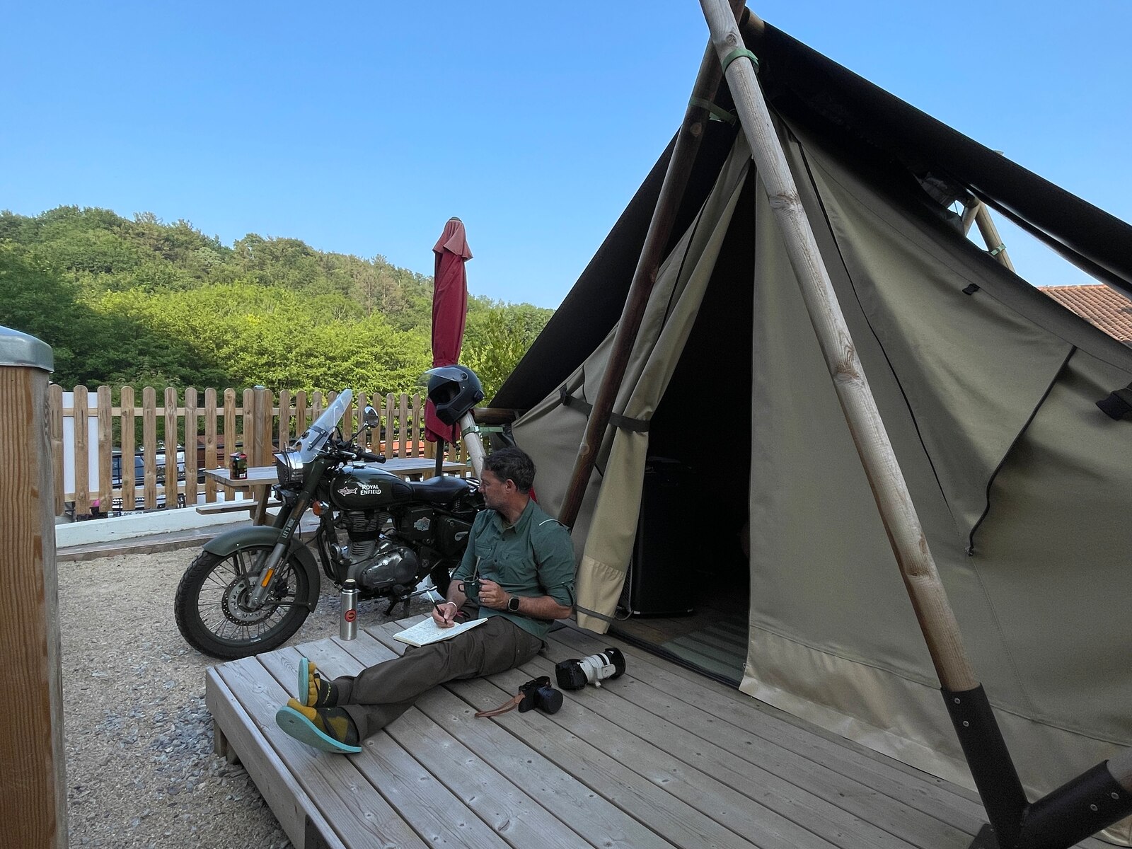 Diego Rosón writing beside his Royal Enfield and camera outside a tent