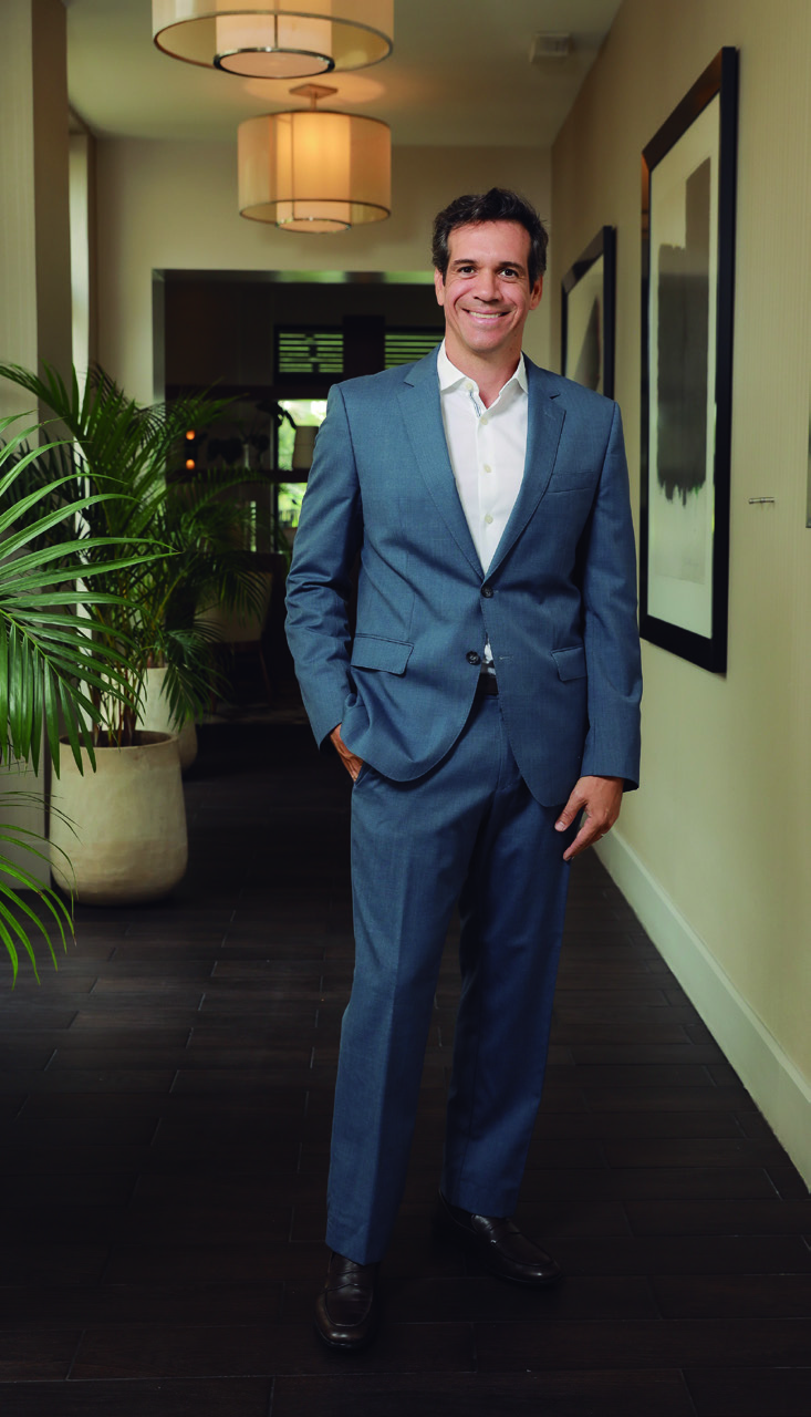 Diego Vallarino smiling in a blue suit in a hotel corridor