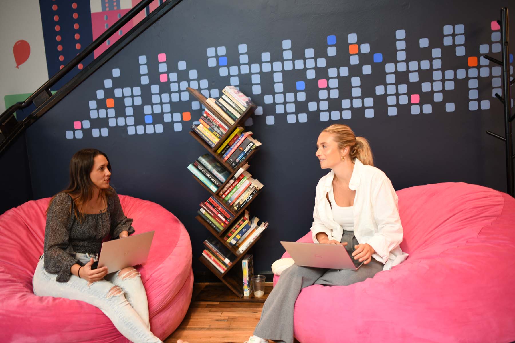 Two Digible employees talking with laptops in the company's colorful office