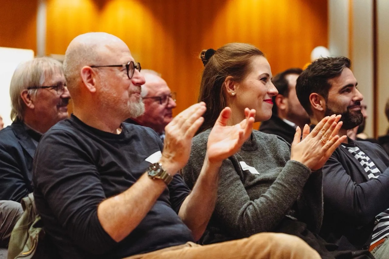 Audience members smiling and applauding at an Ignition event