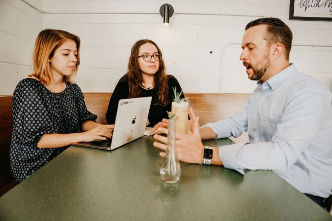 Eric Ritter talks with two Digital Neighbor colleagues around a table