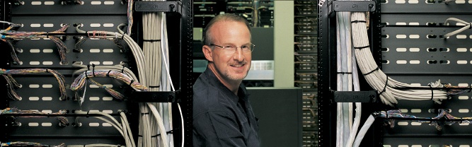 Digital River founder Joel Ronning standing between rows of server racks, pictured in the company’s 2003 annual report.