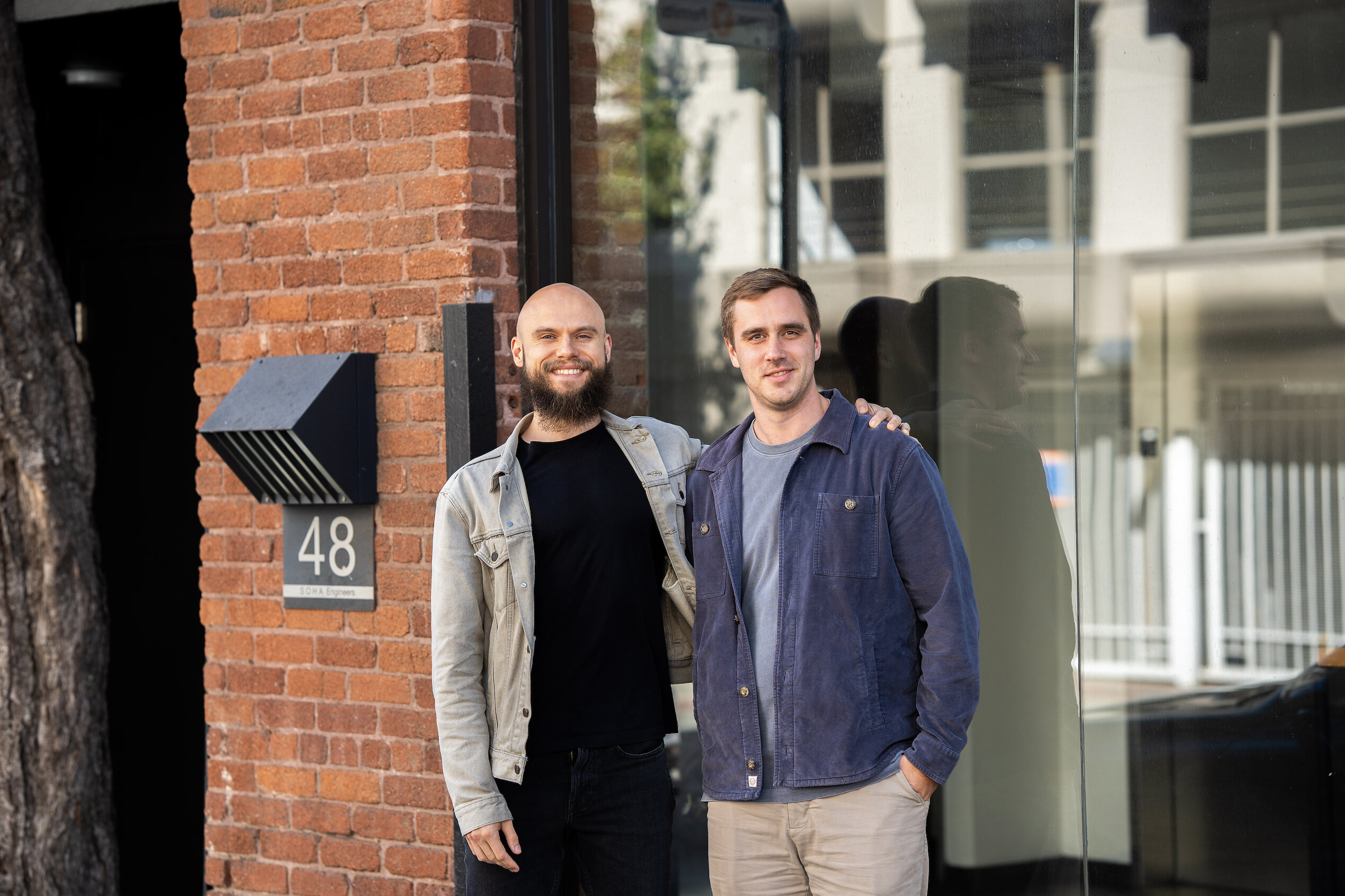 Dima Goncharov, left, and Colin Elsinga standing together outside a brick building