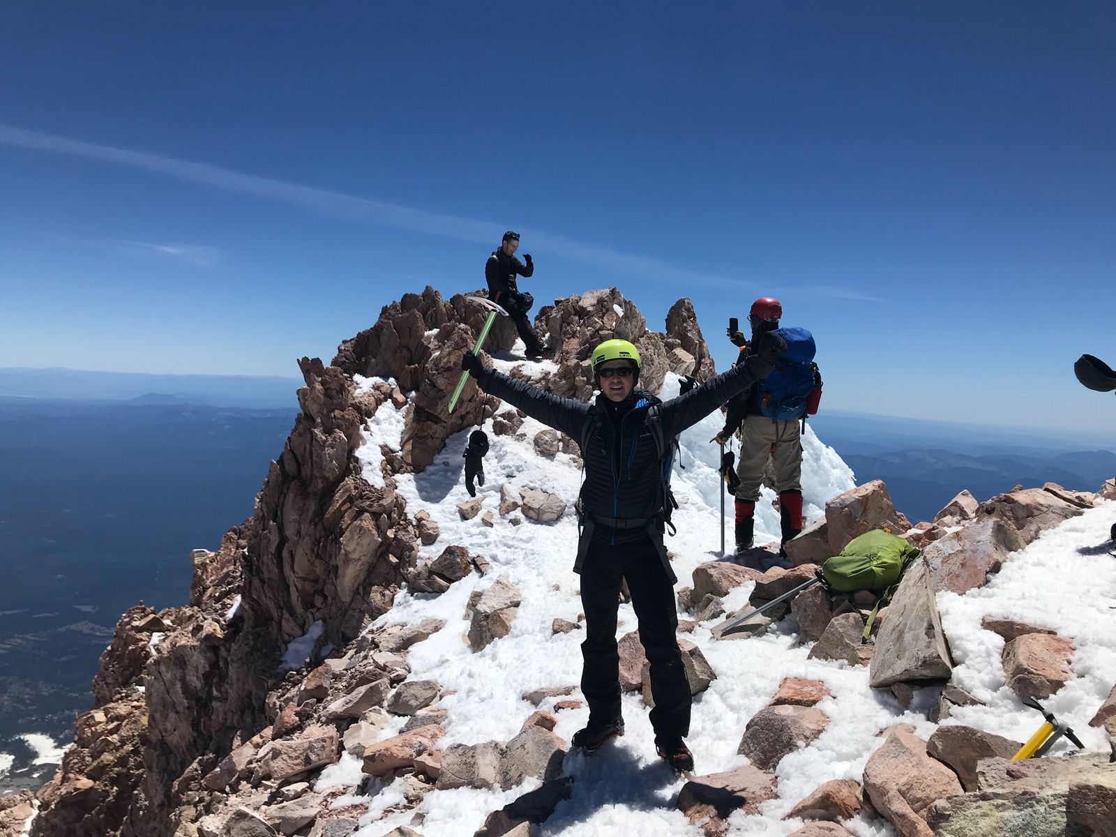 Mitko Simeonov holding an ice axe with arms outstretched on the snowy Mount Shasta summit