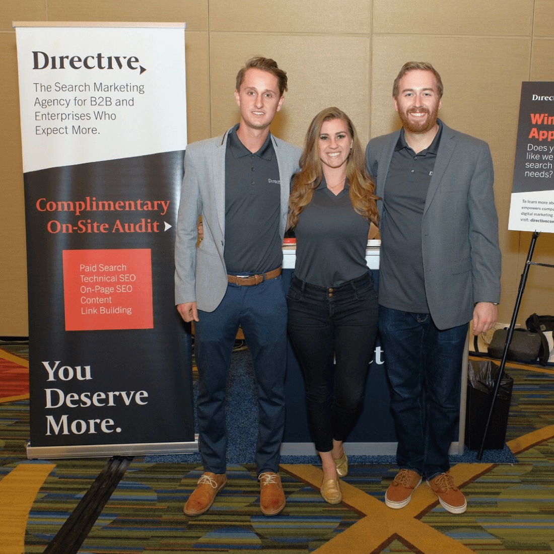 Three Directive team members beside a search marketing display at an industry event
