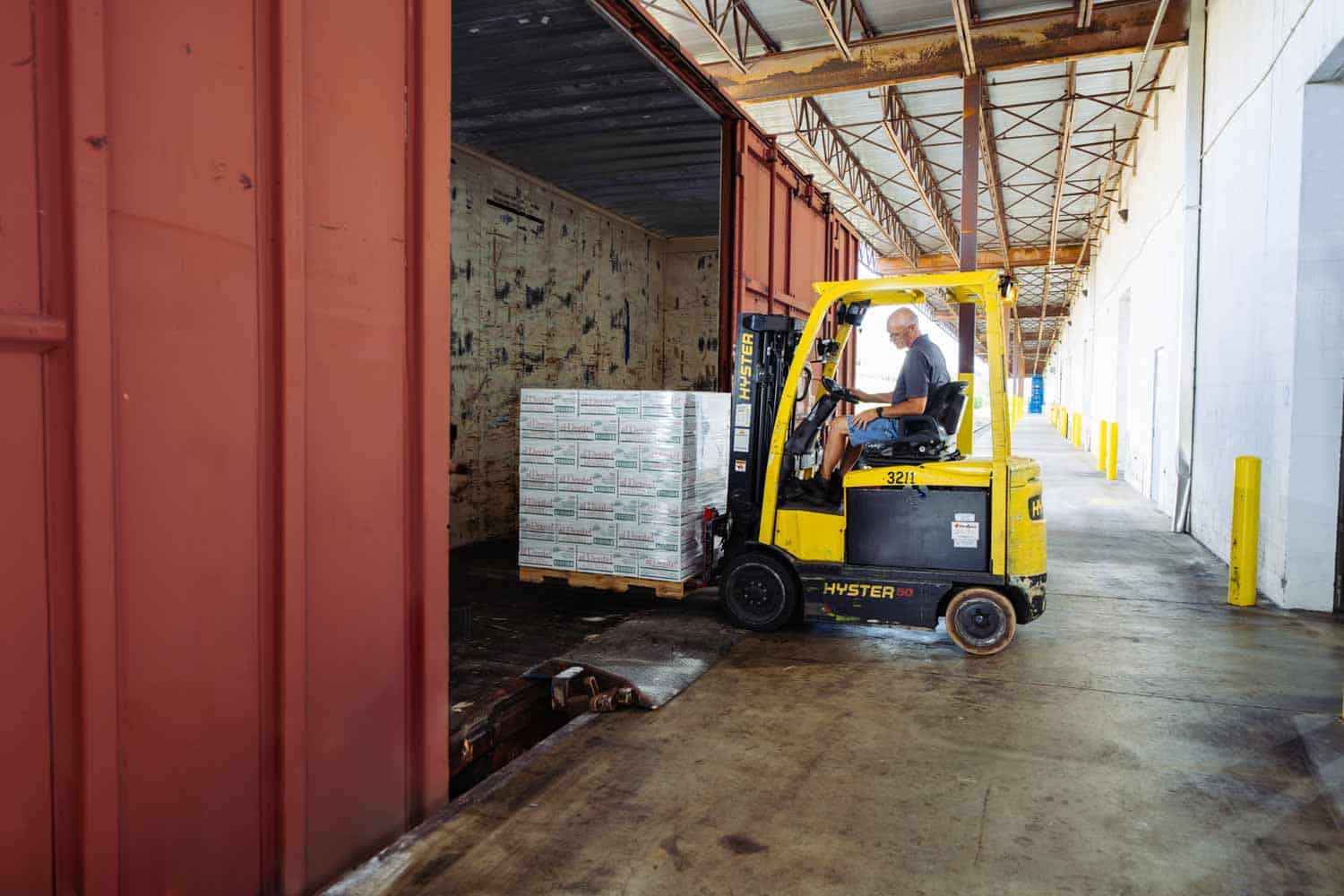 A forklift transfers a pallet at an open railcar in Distribution Technology’s warehouse