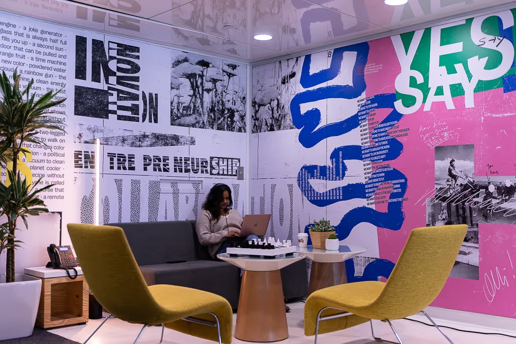 District 3 coworking lounge with yellow chairs, a chessboard and colorful wall graphics