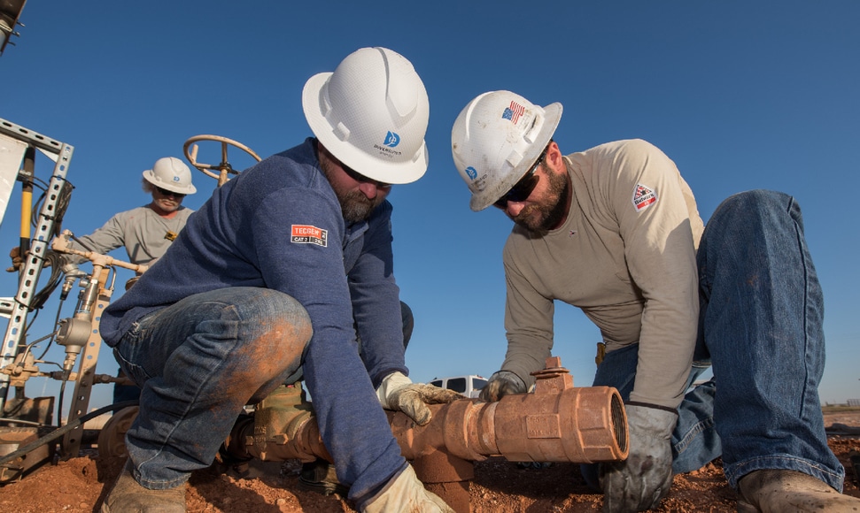 Diversified field workers handling pipe at an operating site