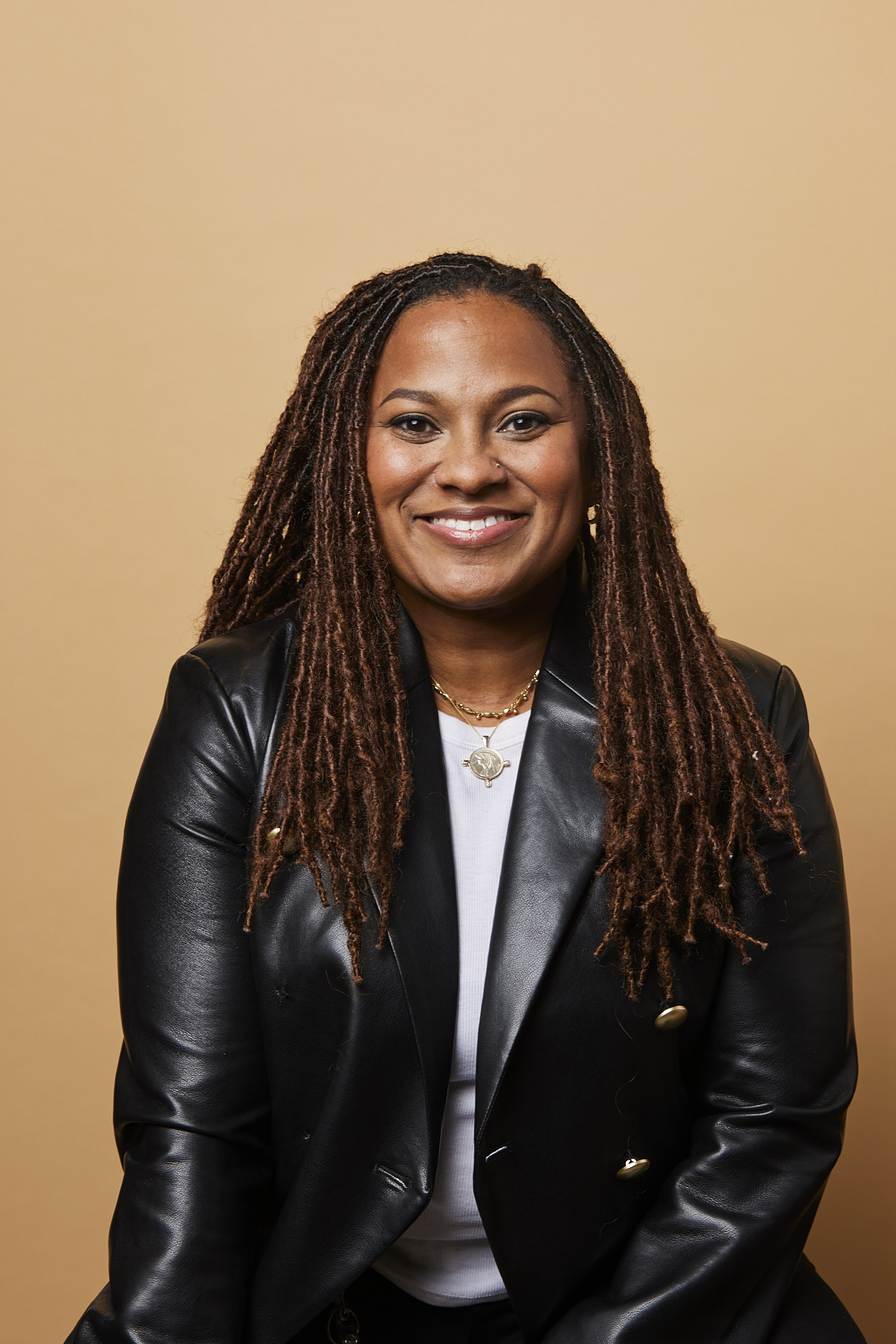 DivInc CEO Tauri Laws-Phillips in a black jacket against a warm tan background
