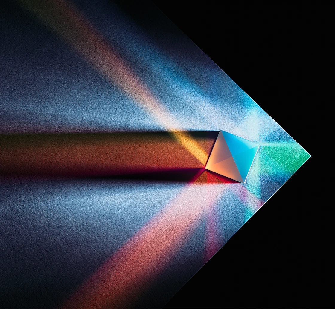 A prism casting colored bands of light across a dark surface