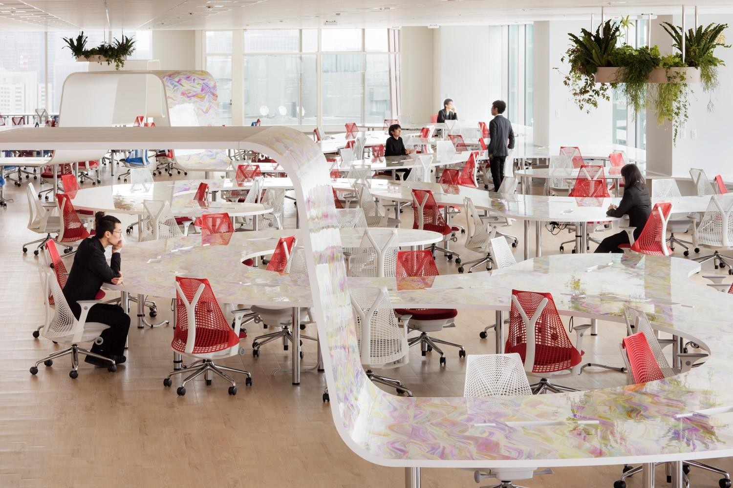 DMM’s bright Roppongi office, with winding iridescent desks, red and white chairs and suspended plants