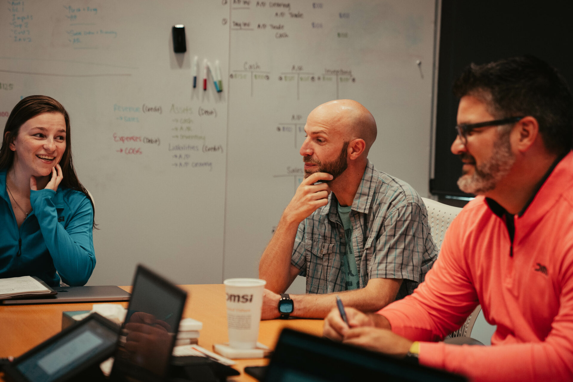 Three DMSi team members discussing work around a meeting table