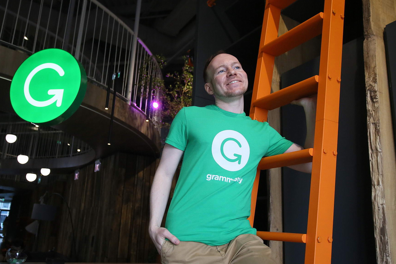 Dmytro Lider standing beside an orange ladder inside Grammarly's Kyiv office