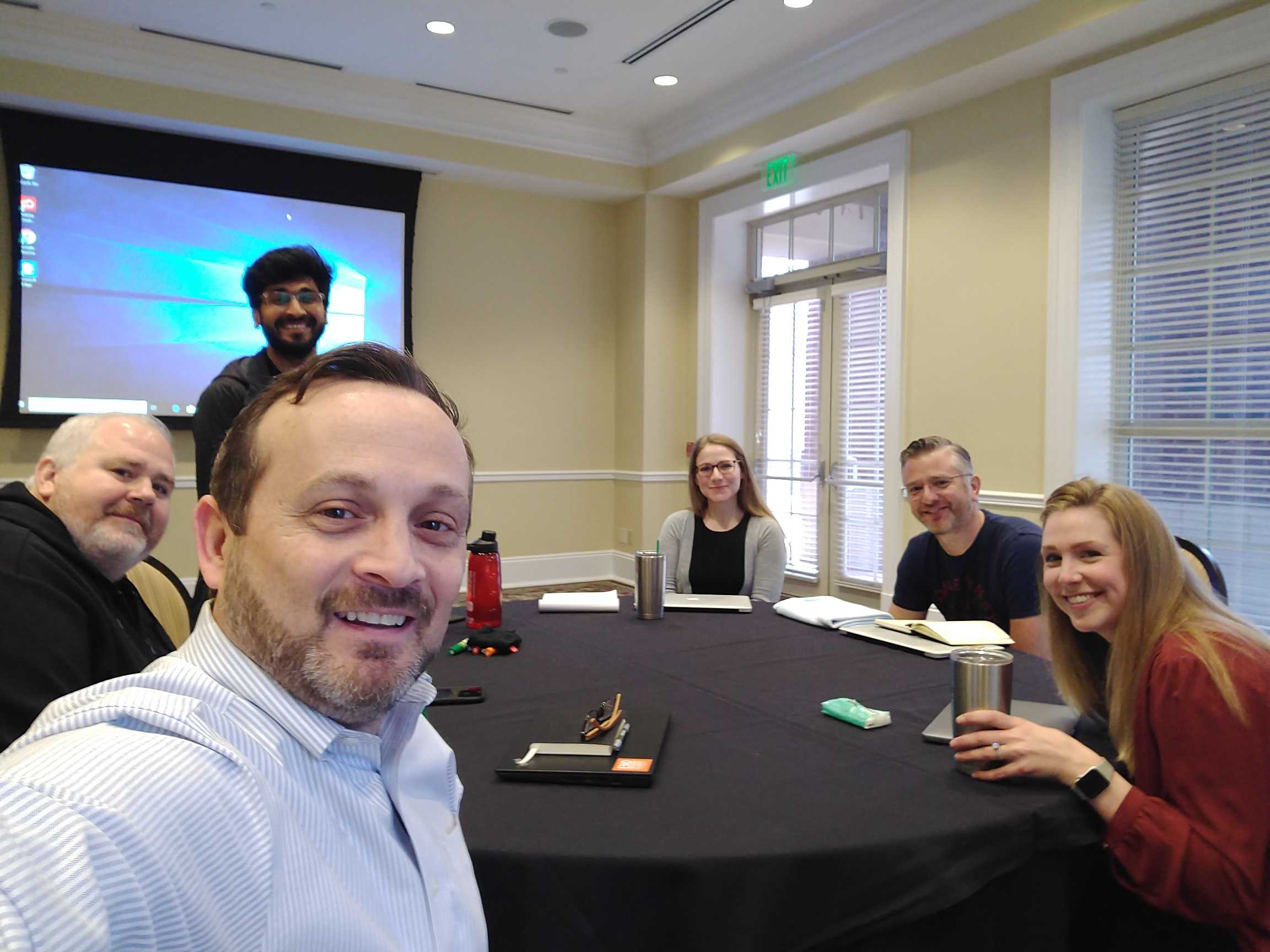 Six members of the ArenaCX team seated around a meeting table, with Doc Shufelt second from the right