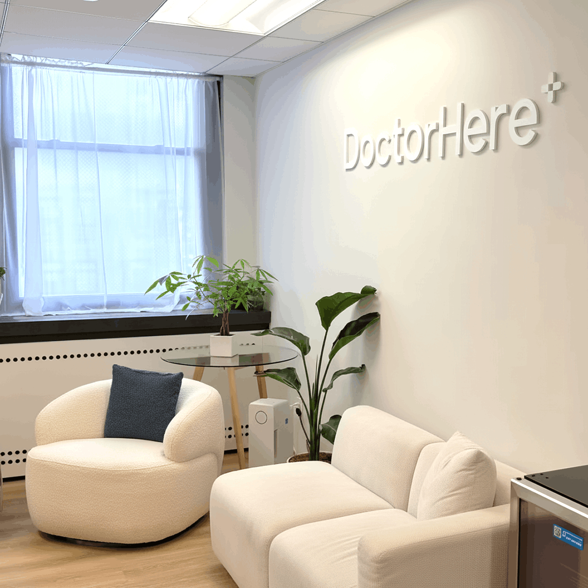 DoctorHere clinic reception room with cream chairs and wall signage