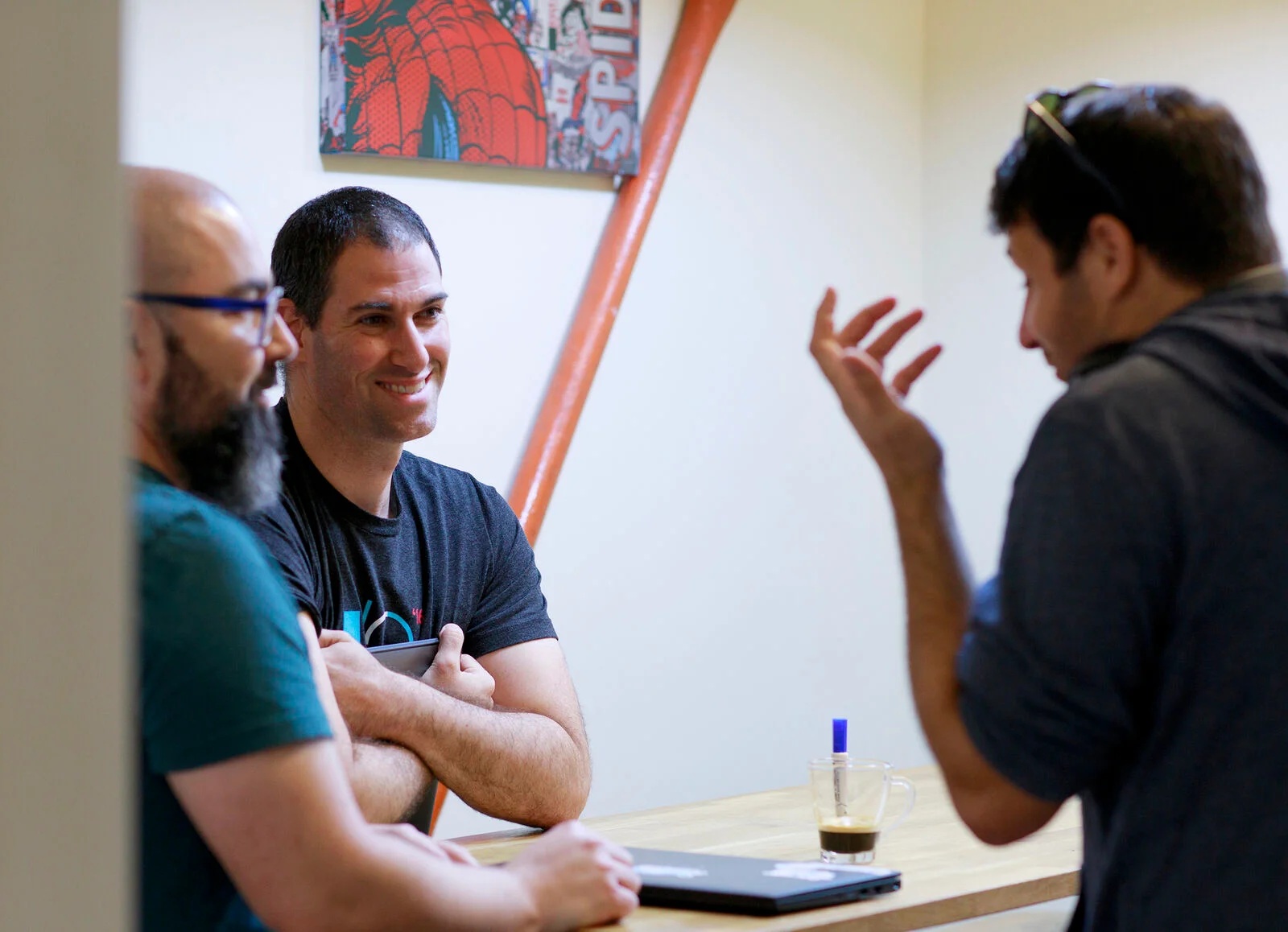 Three people talking around a table in a collaboration photograph published by DoiT